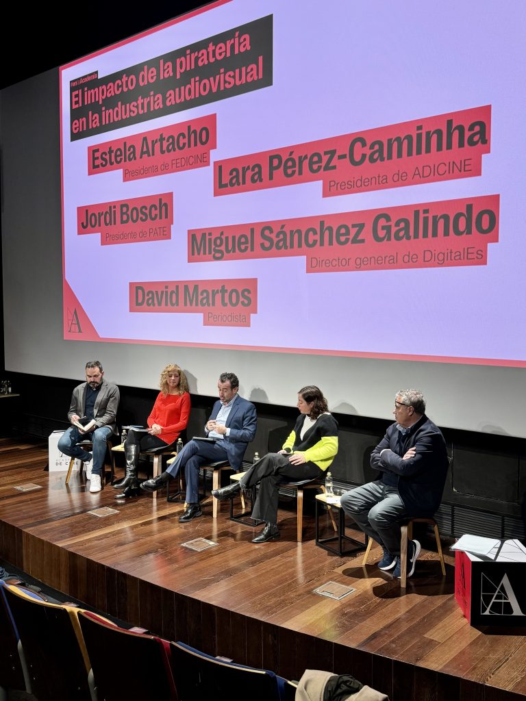 escenario de la jornada de debate de pirateria con los 5 participantes sentados